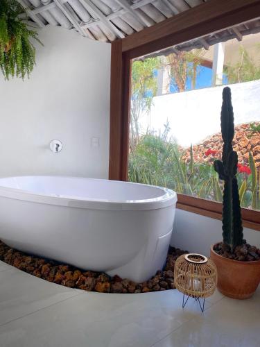 a white bath tub in a bathroom with a cactus at Pousada Ilha do Vento in São Miguel do Gostoso
