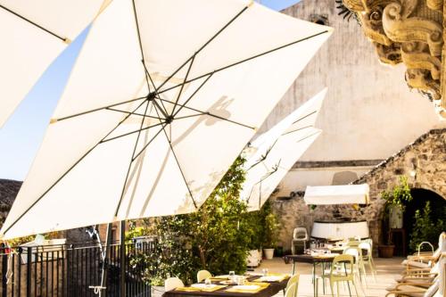 a patio with tables and white umbrellas at Bed and Breakfast Terra del Sole Ibla in Ragusa