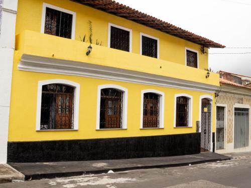 ein gelbes Haus mit weißen Fenstern in der Unterkunft RioSlz Hostel in São Luís