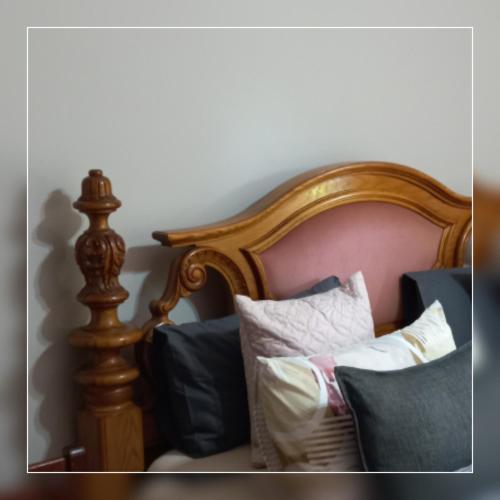 a bed with a wooden frame with pillows on it at A-Cody Place in Louis Trichardt