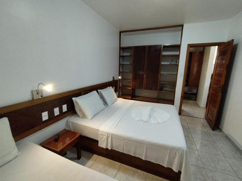 a bedroom with a large white bed and a mirror at Apart Boulevard da Praia 155D in Porto Seguro