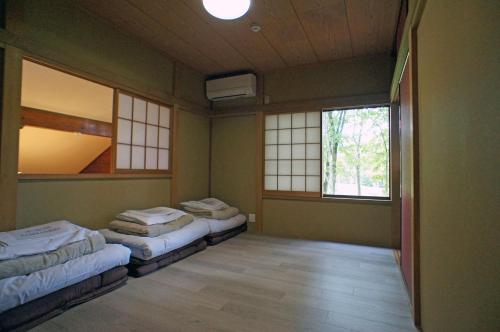 2 Betten in einem Zimmer mit 2 Fenstern in der Unterkunft HARUNA WING Private cottage in the forest overlooking the golf course in Azumaiokozan