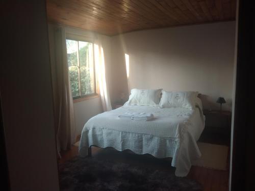 a bedroom with a bed with white sheets and a window at Cabaña acojedora in Zapallar