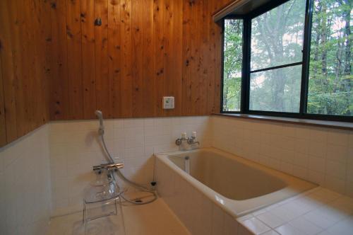 a bath tub in a bathroom with a window at HARUNA WING Private cottage in the forest overlooking the golf course in Azumaiokozan