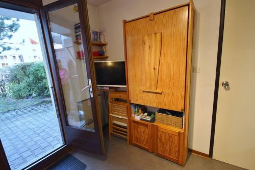 a room with a desk with a television and a wooden cabinet at les 3 marmottes les Glières in Bourg-Saint-Maurice