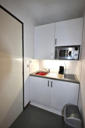 a small white kitchen with a sink and a microwave at les 3 marmottes les Glières in Bourg-Saint-Maurice