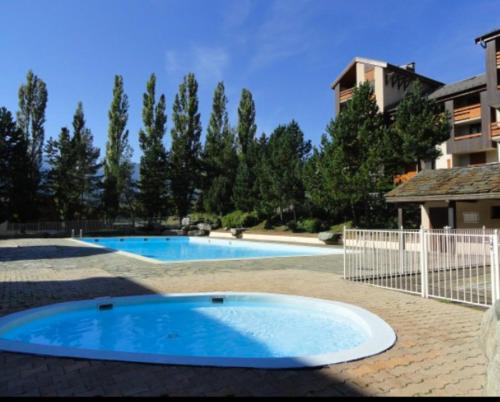 two swimming pools in a yard next to a building at les 3 marmottes les Glières in Bourg-Saint-Maurice
