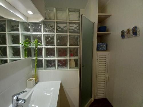 uma casa de banho com um lavatório e um chuveiro com uma janela em Casa da Carmen - Estúdio em Albufeira em Albufeira