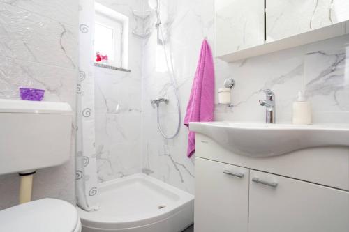 ein weißes Bad mit einem WC und einem Waschbecken in der Unterkunft Apartman LuNi sa bazenom - Malinska, Sveti Anton in Sveti Anton