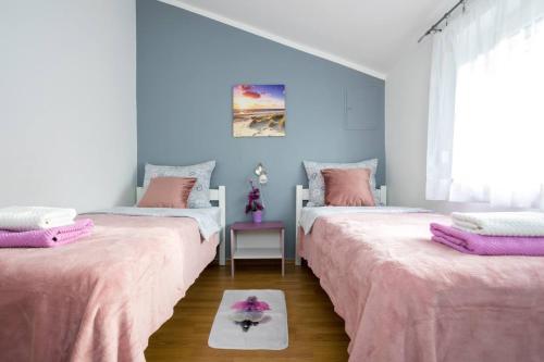 2 Betten in einem Zimmer mit rosa und blauen Wänden in der Unterkunft Apartman LuNi sa bazenom - Malinska, Sveti Anton in Sveti Anton
