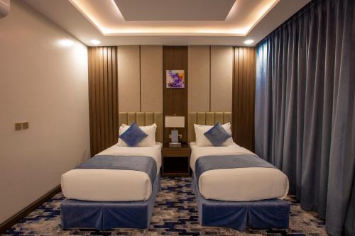 a hotel room with two beds and a desk at فندق امان أبها - المحالة in Abha