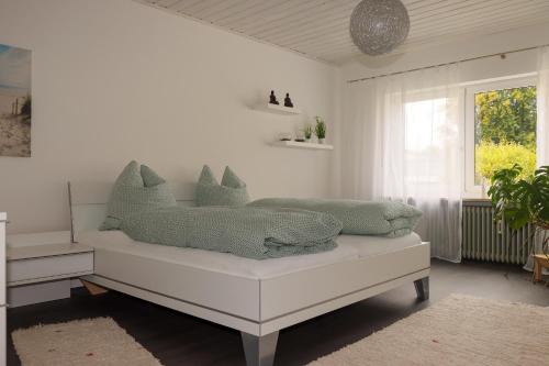 ein weißes Zimmer mit einem Bett mit Kissen darauf in der Unterkunft Buchen Blick - Ruhige moderne Ferienwohnung 82qm. in Fichtelberg