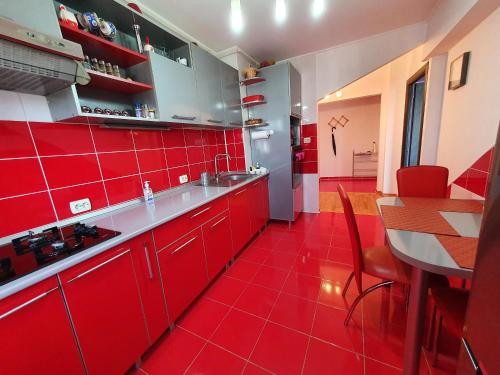 cocina roja con mesa y suelo de baldosa roja en Crema Apartaments, en Ploieşti