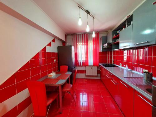 cocina roja con mesa y sillas rojas en Crema Apartaments, en Ploieşti