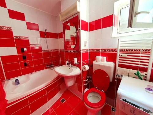 baño rojo y blanco con aseo y lavamanos en Crema Apartaments, en Ploieşti