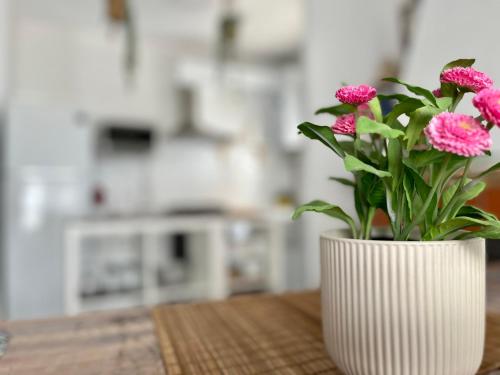 a white vase with pink flowers sitting on a table at Casa Valle del Turia in Chulilla