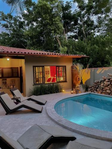 a swimming pool with two lounge chairs next to a house at Villa Balthazar in Búzios