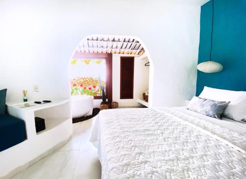 a white bedroom with a white bed and a bathroom at Pousada Ilha do Vento in São Miguel do Gostoso