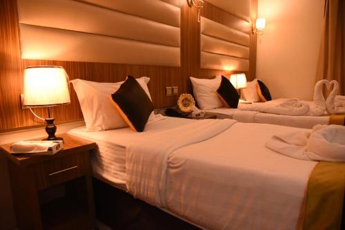 a hotel room with two beds and a lamp at فندق قصر الاندلس الذهبي - Alandalus golden palace Hotel in Al Madinah