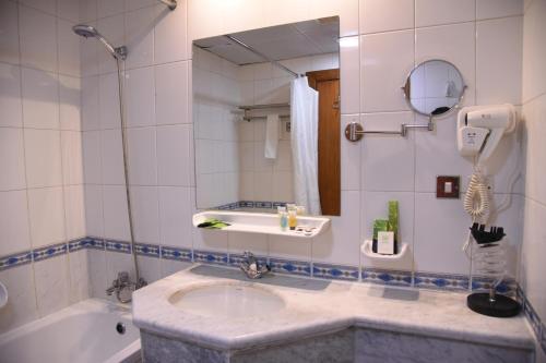 a bathroom with a sink and a tub and a mirror at فندق قصر الاندلس الذهبي - Alandalus golden palace Hotel in Al Madinah