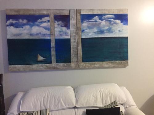 uma pintura acima de um sofá com um barco no oceano em COSTÃO DAS GAIVOTAS: HOSPEDE -SE NO PARAÍSO em Florianópolis
