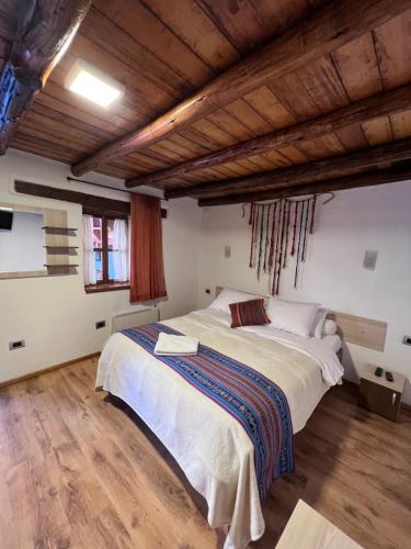 ein Schlafzimmer mit einem großen Bett in einem Zimmer mit Holzdecken in der Unterkunft Casona les Pleiades in Cusco