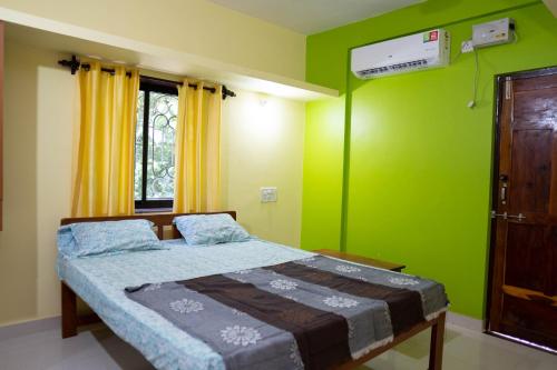 a bedroom with a bed and a green wall at Dhanashree Riverview Hotel in Corgao