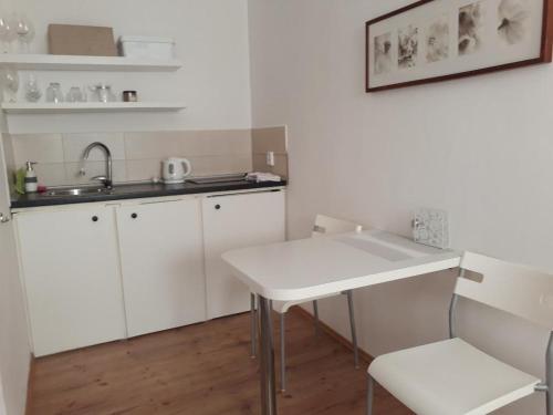 a white kitchen with a sink and a table at ubytovanie CITY apartmán in Martinske Hole