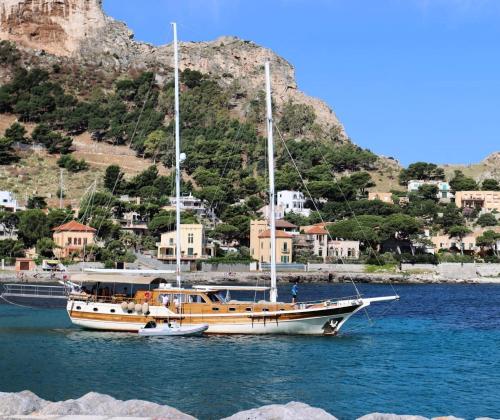 un barco sentado en el agua con una montaña en el fondo en DonnaMarisa, en Palermo