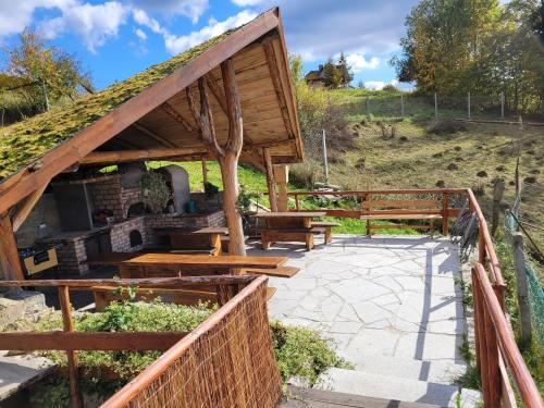 a pavilion with a grass roof with benches and a grill at Apartament u Jawora in Grywałd