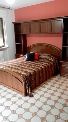 a bedroom with a wooden bed with a red wall at Casa Vacanze in Agliè