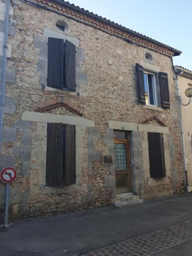 an old brick building with black windows and a door at La Demeure in Gabarret