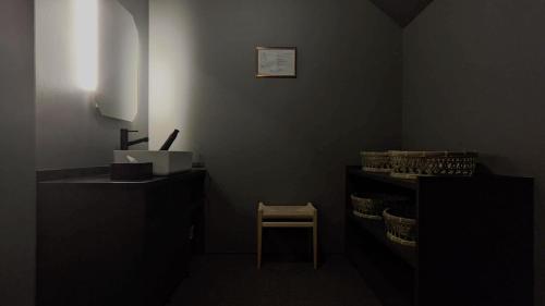 a dark room with a chair and a shelf with glasses at Kobayashiya -Kinosaki Onsen- in Toyooka
