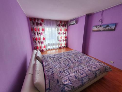 1 dormitorio con paredes moradas, 1 cama y ventana en Crema Apartaments, en Ploieşti