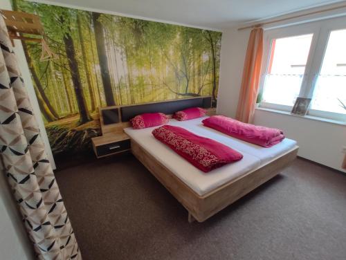 ein Schlafzimmer mit einem Bett mit rosa Kissen und einem Gemälde in der Unterkunft Ferienwohnung Cassiopeia in Harzgerode