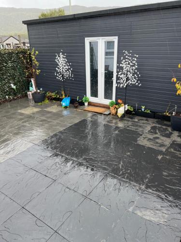 a black house with a concrete driveway in front of it at Craigellachie Cabin in Aviemore