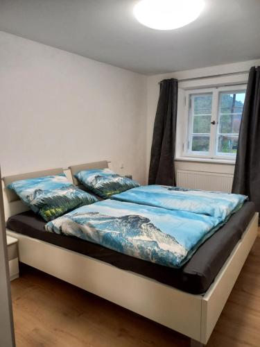 a bedroom with a bed with blue sheets and a window at Zur alten Schmiede in Ettal