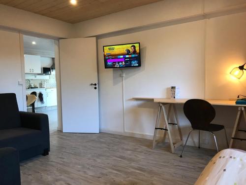 a living room with a table and a tv on the wall at T2 Rdc, jardin, calme, parking, idéalement placé in Issoire