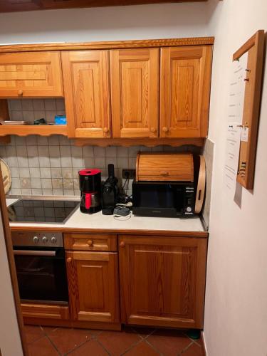 a small kitchen with wooden cabinets and a microwave at Ferienhaus Pfarrerweinzerl in absoluter Ruhelage mit Pool in Kitzeck im Sausal