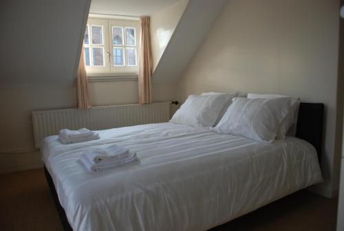 una camera da letto con un letto bianco e asciugamani di Vakantiehuis De Vorster Pastorie a Broekhuizenvorst