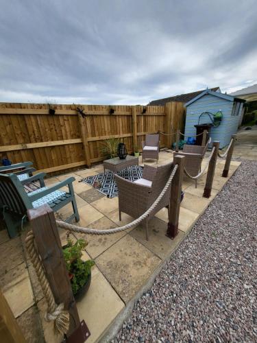 un patio con sillas, mesas y una valla en A great place for you and your dog to stay, en Falmouth
