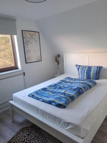 een wit bed met een blauwe deken erop bij FerienhausWeseby in Hürup