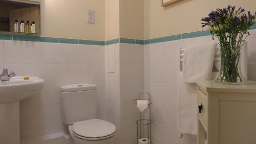 a bathroom with a toilet and a sink and a vase of flowers at Citystay Living- Warren Close in Cambridge