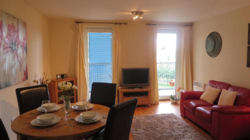 a living room with a table and a red couch at Citystay Living- Warren Close in Cambridge