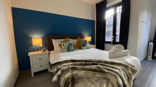 een slaapkamer met een groot bed met een blauwe muur bij Oneluxstay Antwerp City Centre in Antwerpen