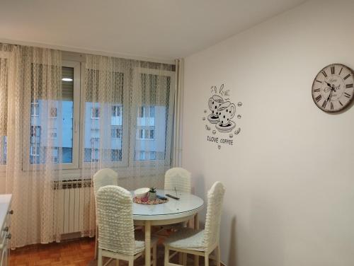 a dining room with a table and chairs and a clock at Apartman F&S - Novo Sarajevo in Sarajevo