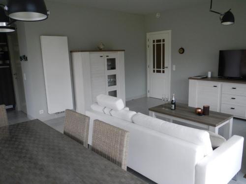 ein Wohnzimmer mit einem weißen Sofa und einem Tisch in der Unterkunft Oostendenachten in Ostende