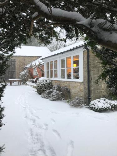 a house in the snow with a snow covered driveway at Norburton Hall Cottages in Bridport