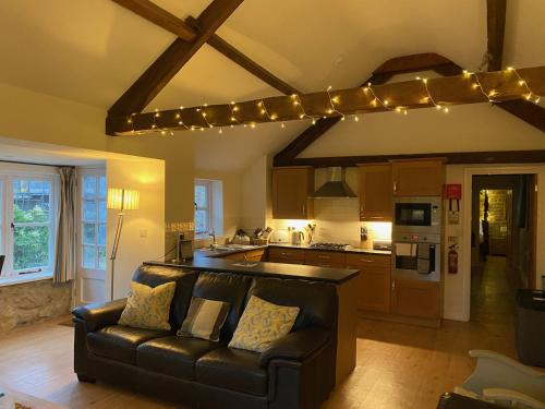a living room with a couch and a kitchen with lights at Norburton Hall Cottages in Bridport