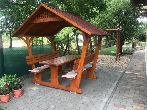 a wooden gazebo with a wooden table and bench at Napfény apartman in Orosháza